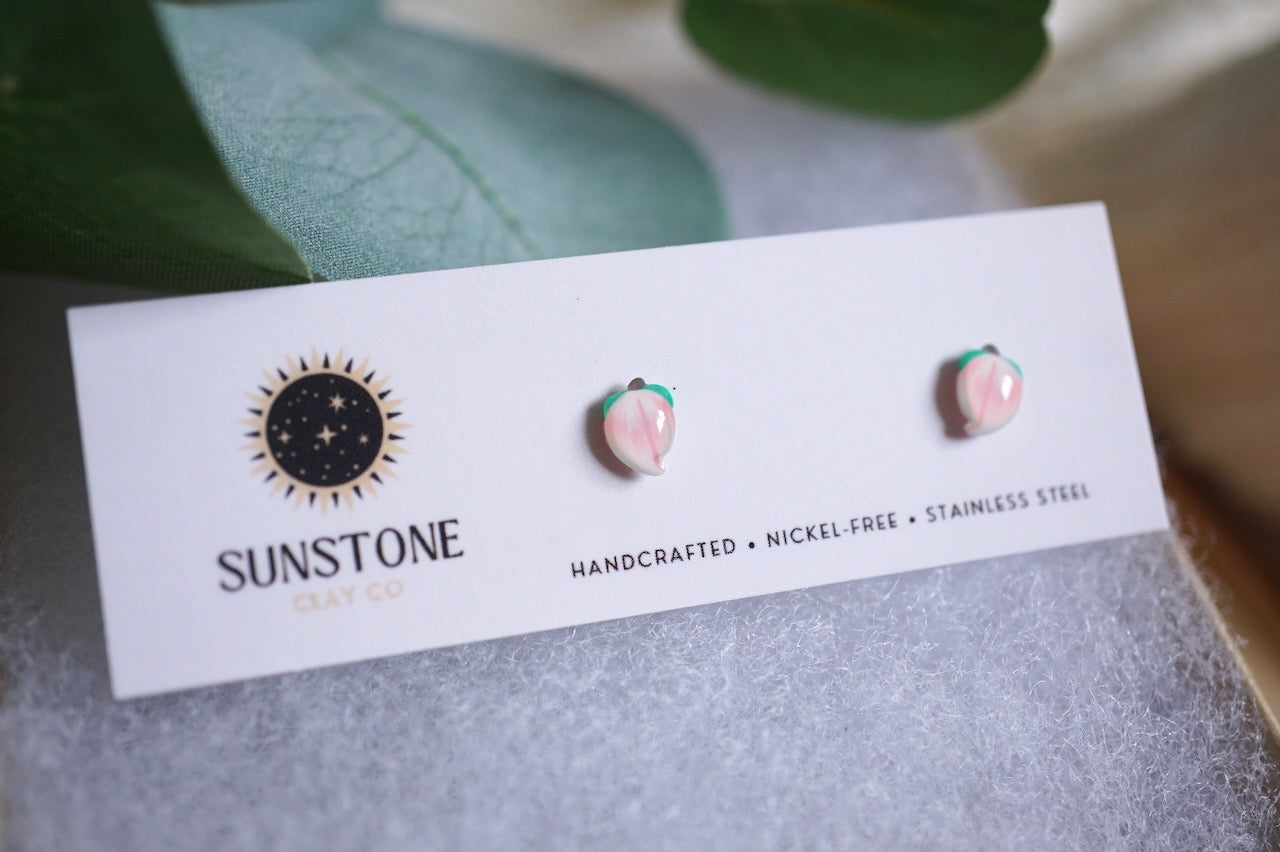 Handcrafted miniature peach stud earrings on display card