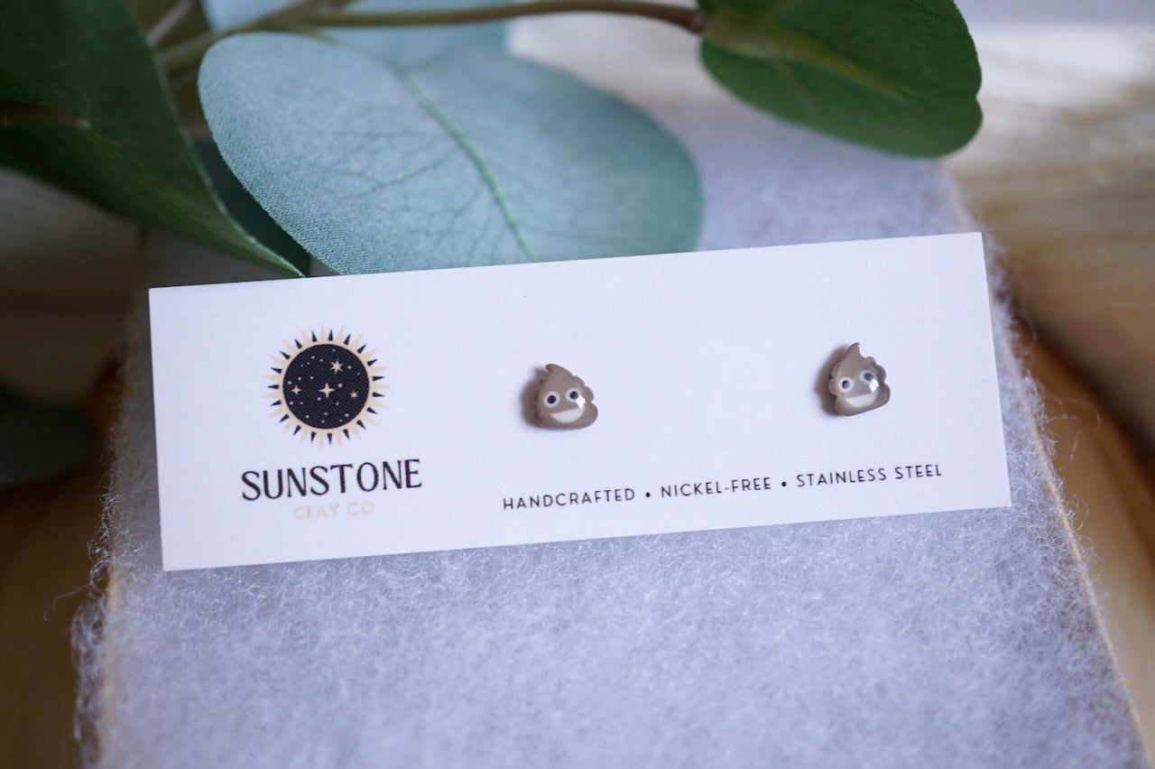 Poop emoji stud earrings on Sunstone Clay Co display card