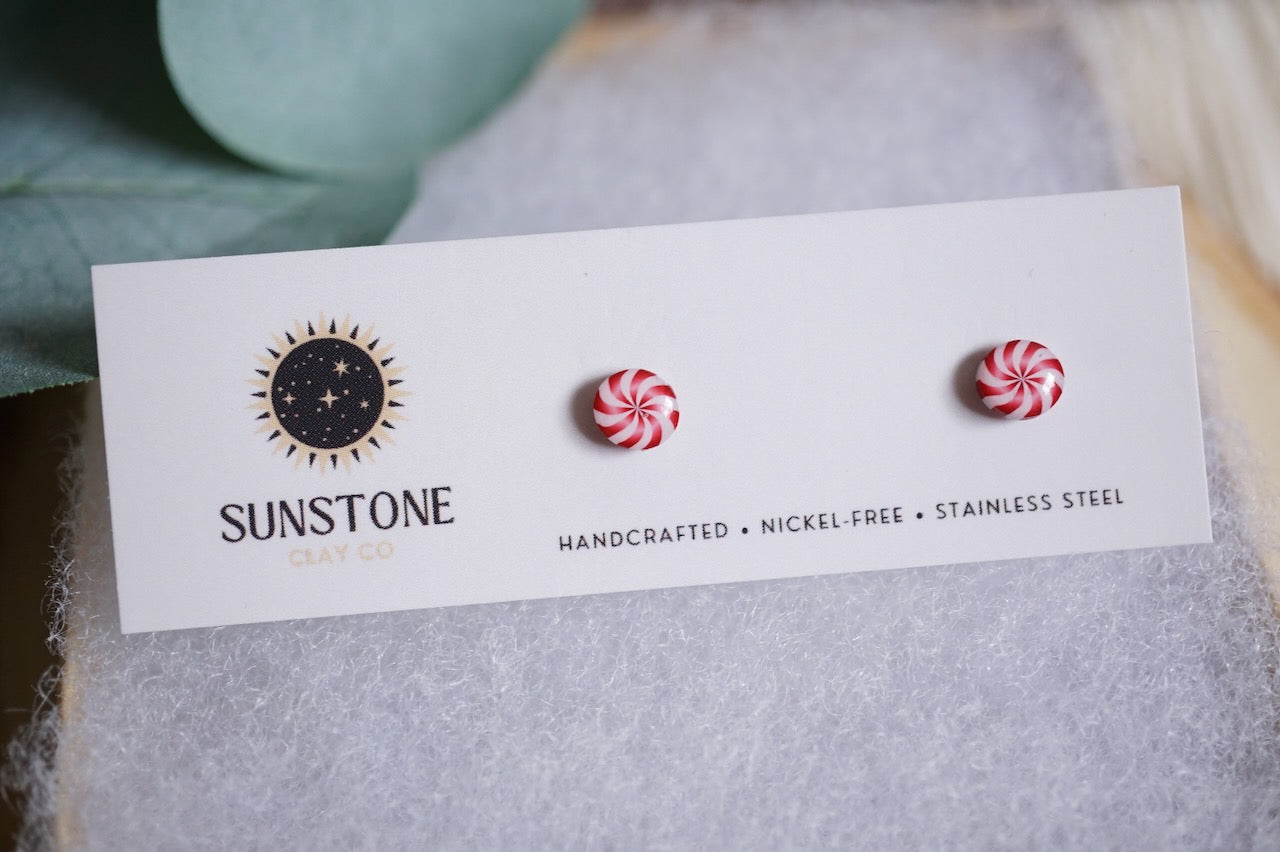 Handcrafted 6mm peppermint swirl stud earrings with red and white candy design on Sunstone Clay Co display card.