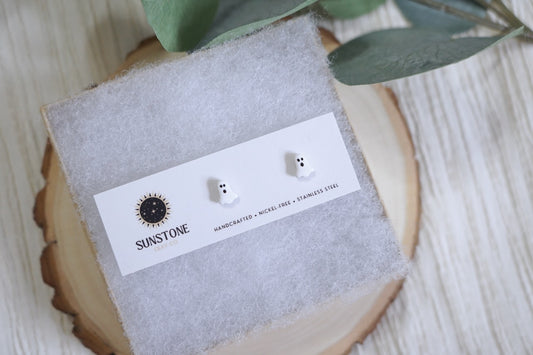 Handcrafted polymer clay ghost stud earrings by Sunstone Clay Co on display card with logo