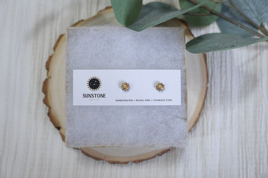 Handcrafted gold sunburst stud earrings by Sunstone Clay Co., on logo jewelry card with soft neutral background.