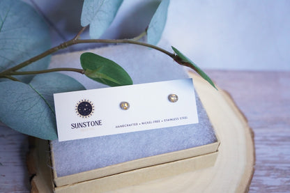 Close-up of handcrafted small 4mm gray and gold stud earrings with stainless steel posts