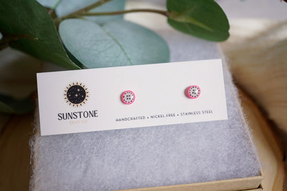 Small handmade dragon fruit slice stud earrings displayed on Sunstone Clay Co card.