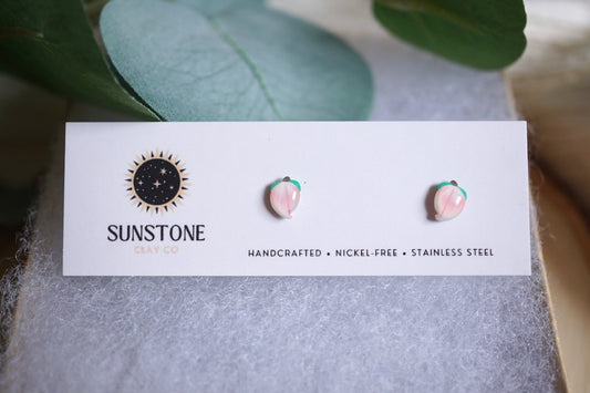 Handcrafted miniature peach stud earrings on display card