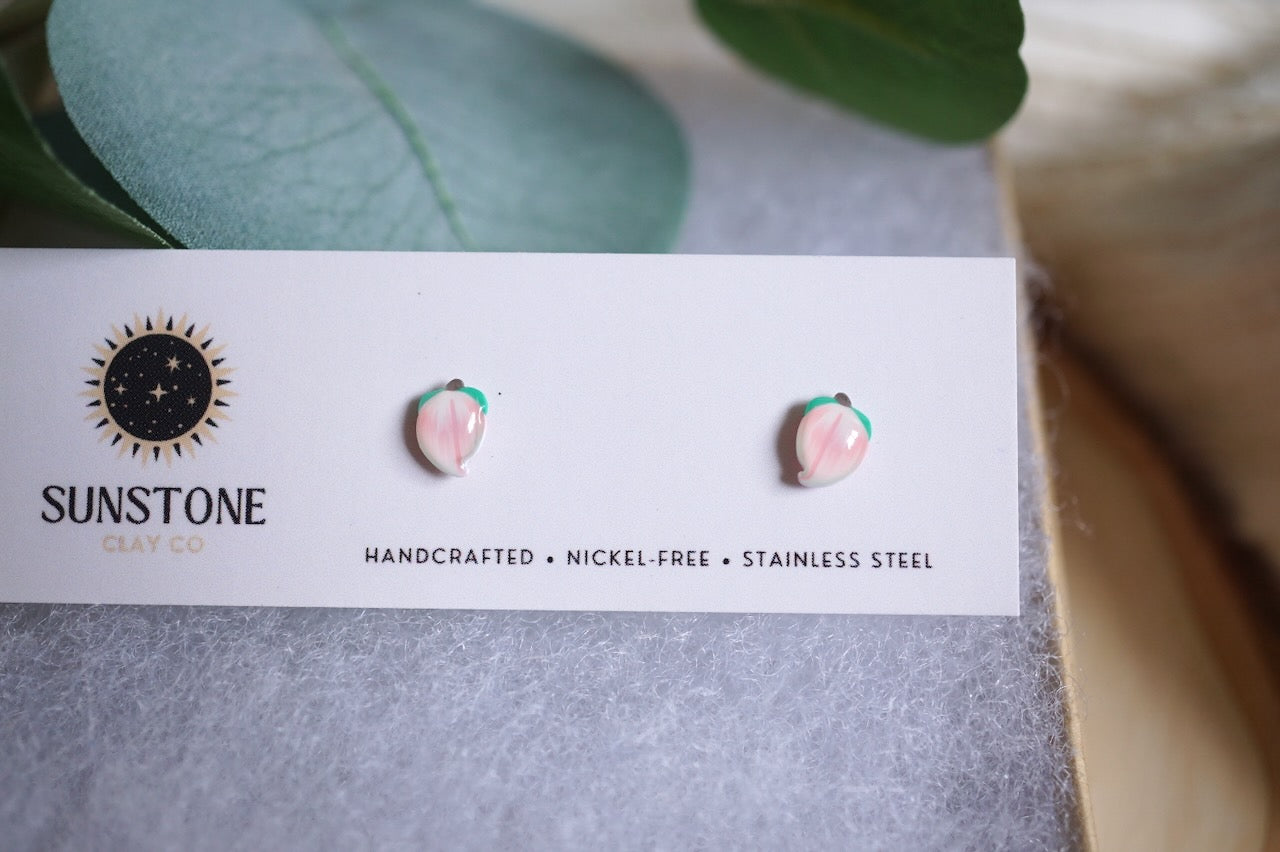 Handcrafted miniature peach stud earrings on display card