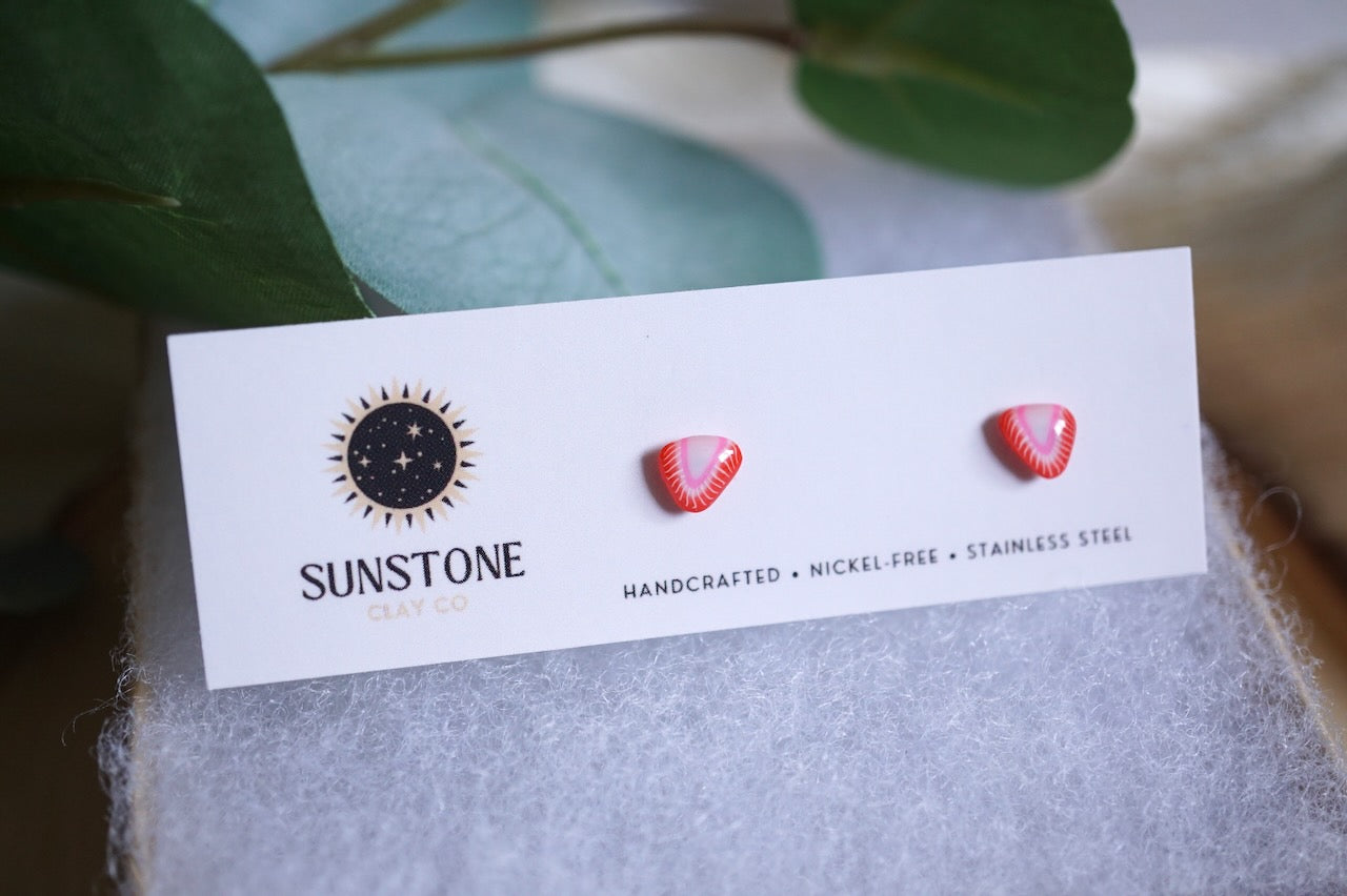 Small handcrafted strawberry slice stud earrings on Sunstone Clay Co card