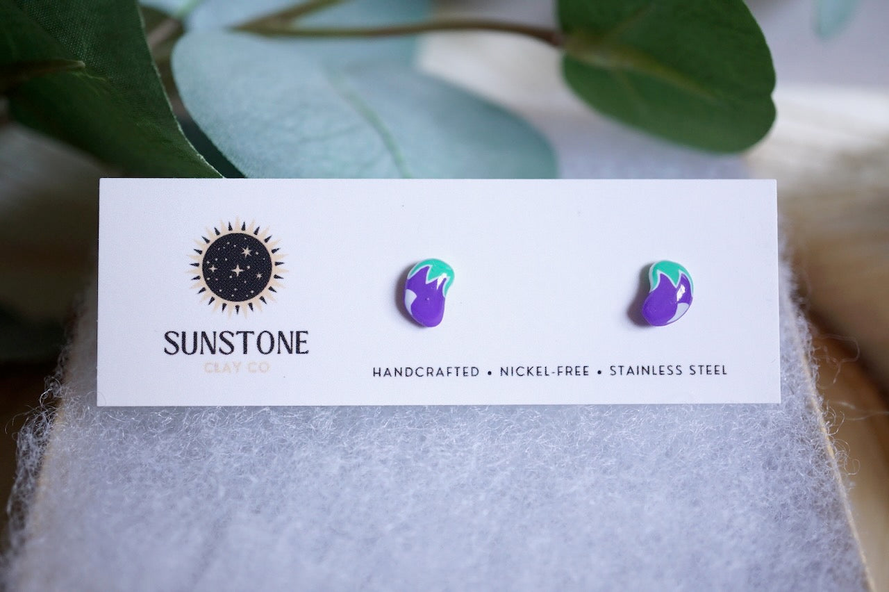 Purple polymer clay eggplant earrings with green tops on white background
