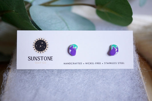 Purple polymer clay eggplant earrings with green tops on white background