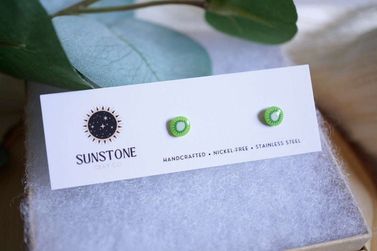 Handcrafted tiny kiwi slice stud earrings on Sunstone Clay Co display card