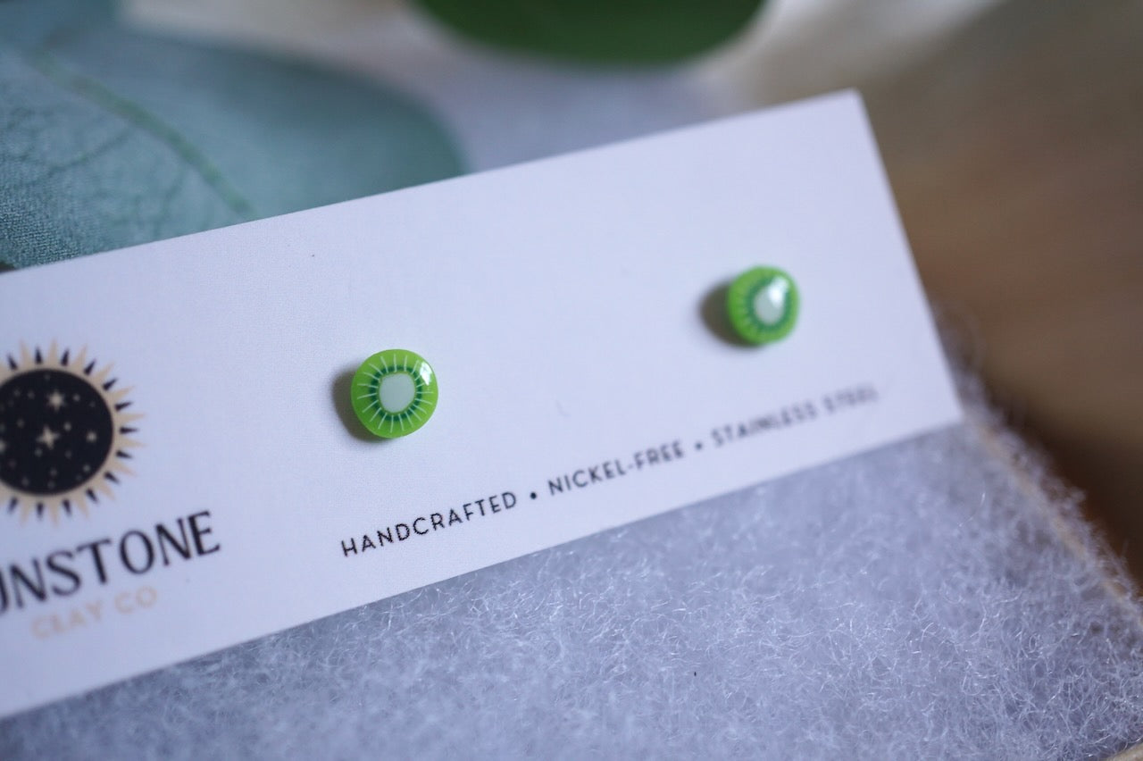 Handcrafted tiny kiwi slice stud earrings on Sunstone Clay Co display card