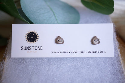 Poop emoji stud earrings on Sunstone Clay Co display card