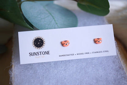 Handcrafted polymer clay tiger face stud earrings displayed on a jewelry card