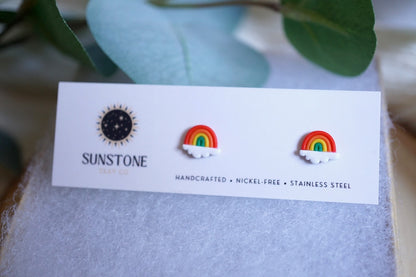 Pair of rainbow earrings on a Sunstone card with leaves in the background