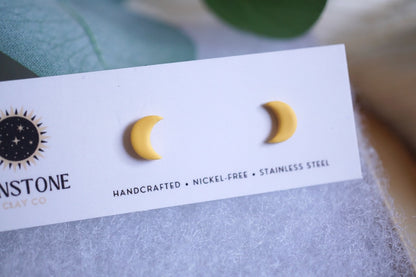 Yellow crescent moon stud earrings on Sunstone Clay Co display card