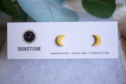 Yellow crescent moon stud earrings on Sunstone Clay Co display card