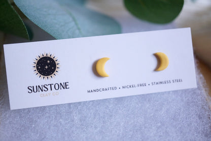 Yellow crescent moon stud earrings on Sunstone Clay Co display card