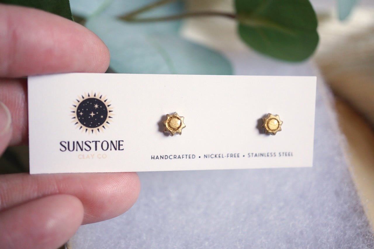 Sunstone earrings on a card held by a hand with a blurred background