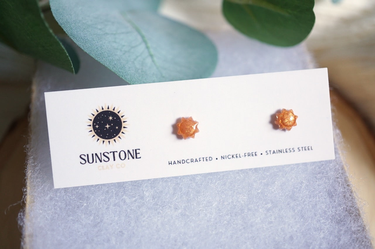Sunstone earrings on a branded card with green leaves in the background