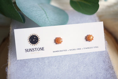 Sunstone earrings on a branded card with green leaves in the background
