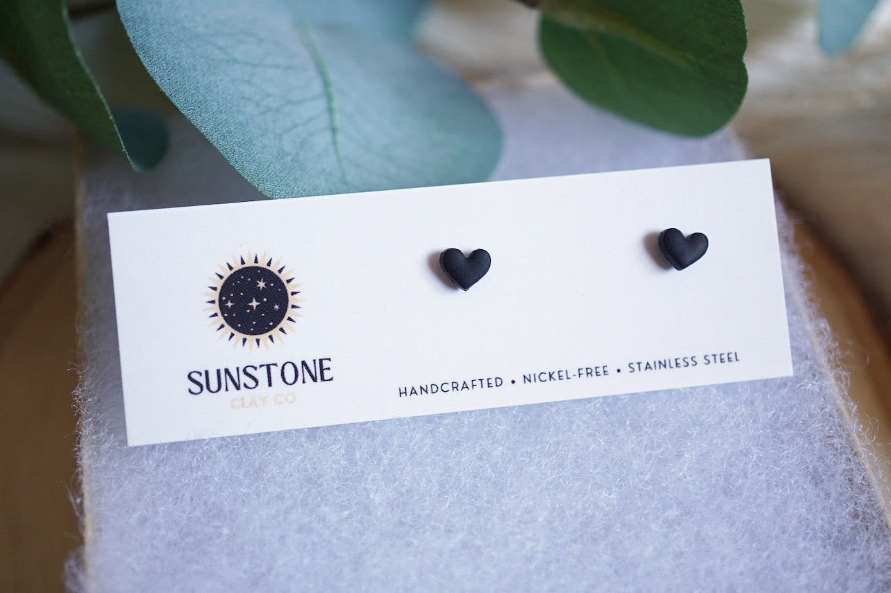 Handcrafted black heart stud earrings on Sunstone Clay Co display card