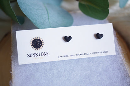 Handcrafted black heart stud earrings on Sunstone Clay Co display card