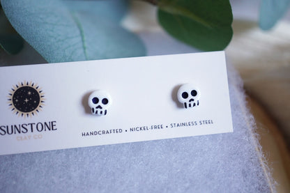 Skull-shaped earrings on a Sunstone branded card with eucalyptus leaves in the background.