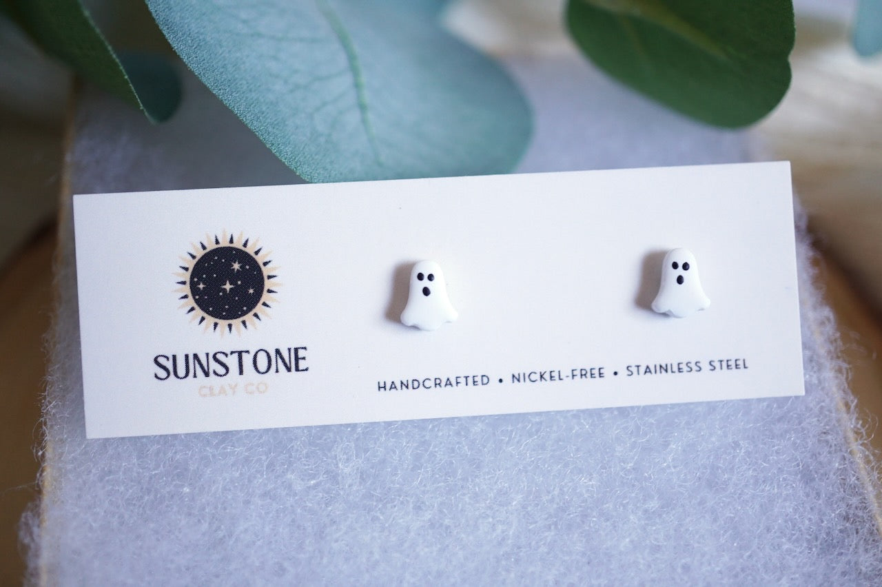 Ghost-shaped earrings on a Sunstone branded card with leaves in the background