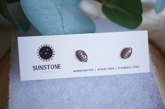 Handcrafted football stud earrings from Sunstone Clay Co. Small-batch polymer clay minis with hypoallergenic stainless steel posts. Perfect for sports lovers, gifts, and game-day style.