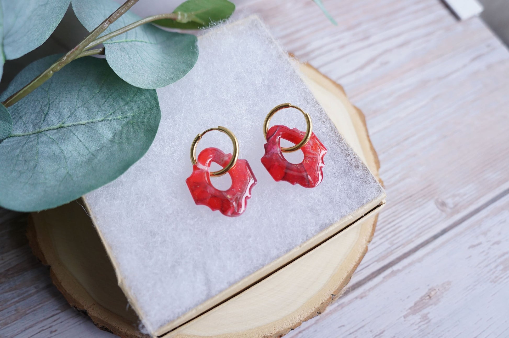 Artisan red and gold earrings styled on soft background