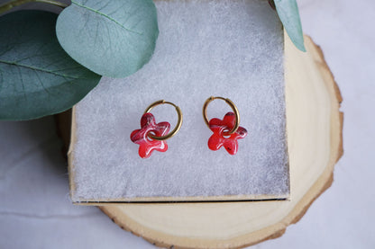 Red flower polymer clay earrings with gold hoops on neutral display