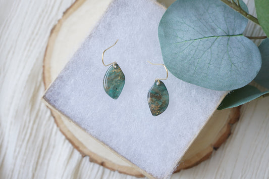 Handmade Gilded Tides Flow earrings with elongated deep teal and emerald green polymer clay pendants, gold marbling and delicate gold-tone hooks.