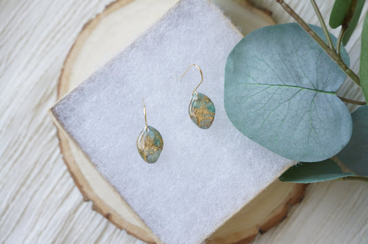 Close-up of Gilded Tides Drift earrings showing glossy turquoise faux-stone polymer clay with unique shimmering gold marbling and irregular organic shapes.