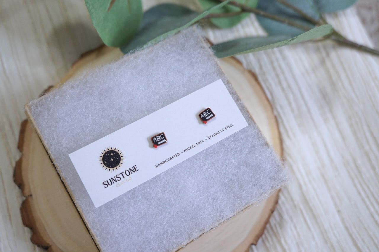 Mini chalkboard stud earrings with apple and chalk details on Sunstone Clay Co card